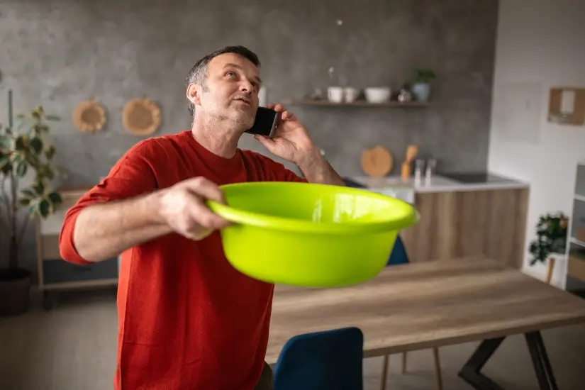 A man holds a bowl to capture water from a leaking roof in Alabama or the Florida Panhandle