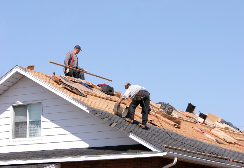 Roofing crew replacing shingles and repairing wooden roof structure on a residential home in Montgomery, AL