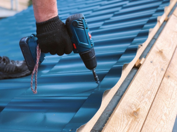 Installing metal roofing panels during a residential roof replacement project